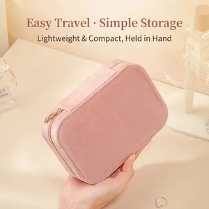 Pink velvet travel jewelry case with gold zipper held in hand for portable storage