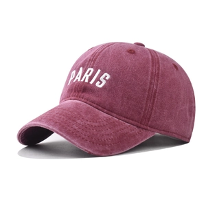 Detail of embroidered white PARIS lettering on washed burgundy cotton baseball cap