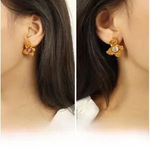 Detailed close-up of gold lava texture earrings with purple and white gemstones