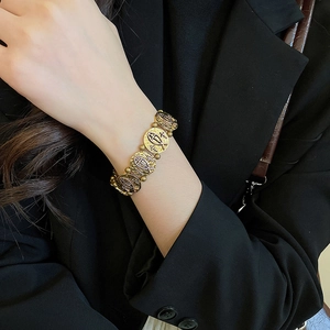 Detail of vintage gold metal bracelet featuring embossed religious cross icons and texture