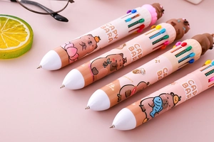 Close-up of 10-color Capybara ballpoint pen with 3D topper on a pastel pink background