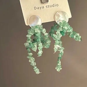 Detail of floral tassel earrings featuring green natural stone beads and white shell studs