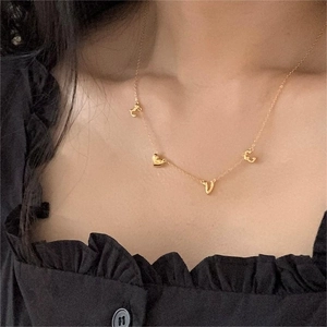 Close-up of gold LOVE letter and heart pendant necklace worn on model neck
