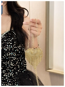 Detail view of heart-shaped gold evening clutch with rhinestones and tassel fringe