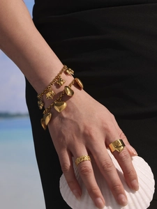 Detailansicht eines goldenen Edelstahl-Charm-Armbands mit Elefanten- und Kleeblatt-Motiv