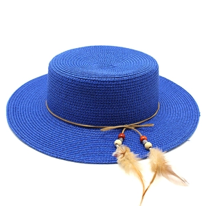 Detail view of royal blue straw boater hat with leather cord, beads and feathers decoration