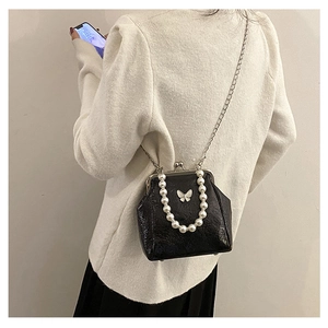 Rear view of model wearing a black pearl strap mini bag with metallic butterfly buckle