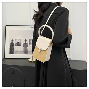 Chic two-tone shoulder bag with round handle and metal clasp shown in a modern interior