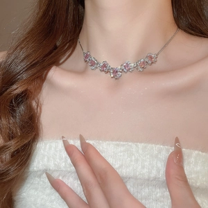 Detailed macro shot of silver necklace with pink square zircon flower pendant on collarbone