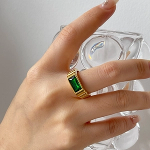 Elegant gold ribbed ring with emerald cut green zircon stone worn by a female model