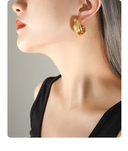 Close-up of chunky gold C-shaped hoop earrings with polished mirror finish on model