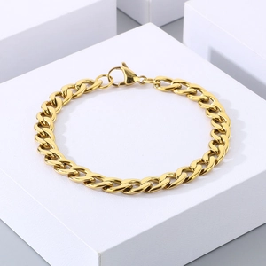Detailed view of gold stainless steel Cuban chain bracelet on geometric blocks