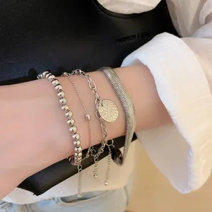 Ensemble de quatre bracelets superposés argentés avec chaînes à billes et pendentif rond