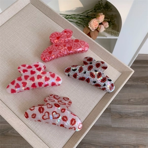 Detail of red heart and lip pattern hair claws on a tray in soft natural light
