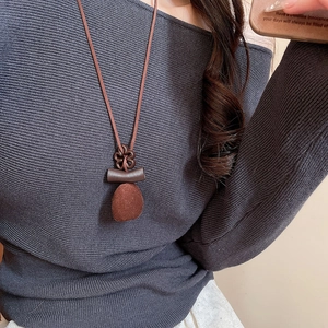 Detail of vintage brown flocked resin pendant necklace on a grey knit sweater