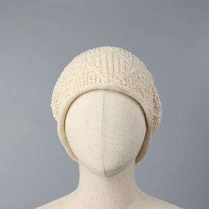 Close-up of beige knit beanie featuring crochet hollow diamond texture and rolled edge