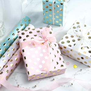 Pastel gift wrapping paper rolls with gold foil polka dots and pink decorative ribbons