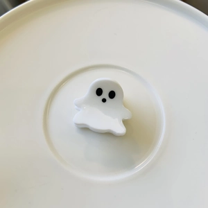 Close-up of white acetate ghost hair clip with black eyes on a minimalist white tray