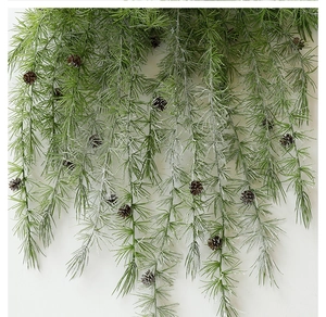 Detail of hanging artificial pine needles with cones and frosted snow for holiday decor