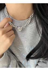 Close-up of double-layered gray pearl necklace with square shell pendant on a model