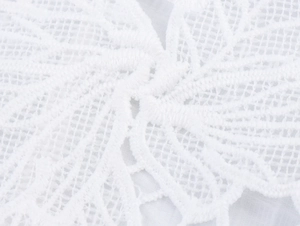Macro view of white lace fabric with intricate floral embroidery and mesh texture details