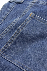 Détail d'un jean taille haute montrant les doubles surpiqûres et la texture du denim