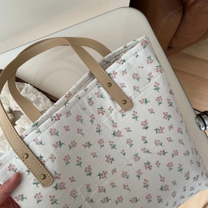 Gros plan du sac cabas floral en coton avec anses en cuir et rivets métalliques