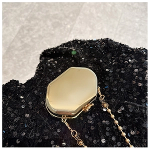 Macro view of gold metal mini bag featuring black sequins and fine gold chain strap