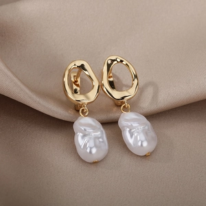Macro shot of baroque pearl earrings with golden geometric metal on champagne satin