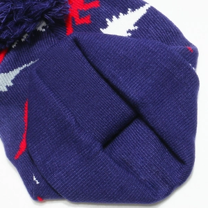 Detailed knit texture of children's purple winter hat with pompom and jacquard patterns