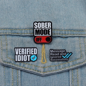Lot de pin's en émail avec slogans humoristiques fixés sur une veste en jean