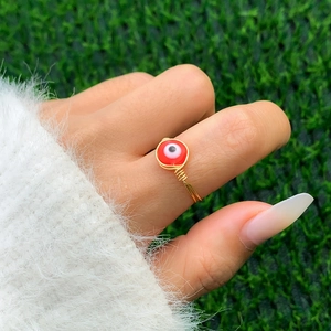 Macro detail of a handmade gold wire-wrapped ring with a red Evil Eye charm bead