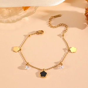Gold stainless steel bracelet with black and gold clover charms and clear gemstones