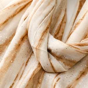 Close-up of beige and brown tie-dye scarf with gold foil accents and raw edge texture