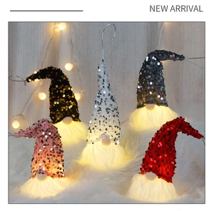 Detail of five colorful sequined Christmas gnomes with warm LED light and hanging strings