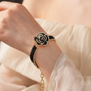Detailed view of a black rose bracelet with gold chain and sparkling rhinestones