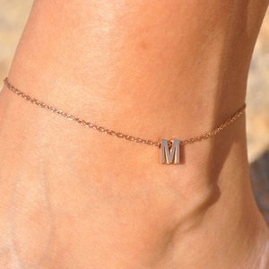 Close-up of rose gold stainless steel anklet with letter M pendant detail