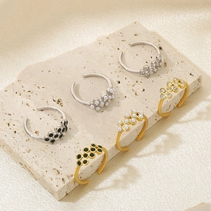 Close-up of pearl and diamond open rings in gold and silver finish on stone display