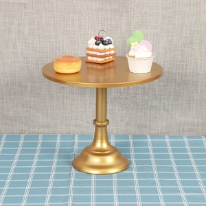 Elegante soporte para tartas de metal dorado sobre mantel de cuadros azules