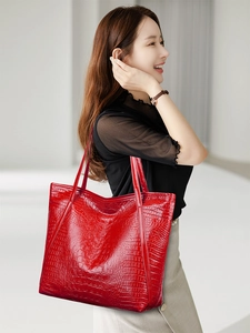 Detailed view of red crocodile-pattern tote bag showing texture and shoulder strap fit