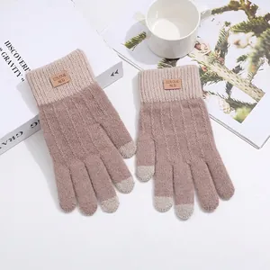 Detail of pink knitted touchscreen gloves with ribbed cuffs and leather brand patch