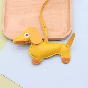 Macro detail of a yellow leather dachshund bag charm with high-quality litchi grain texture