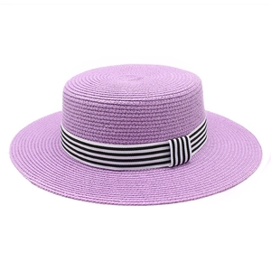 Detail of purple flat top straw boater hat with black and white striped ribbon