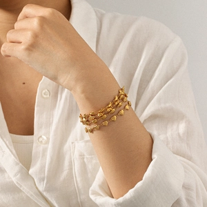 Gros plan du bracelet doré multicouche avec cœurs porté élégamment sur une chemise blanche