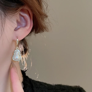 Detailed view of elegant gold gourd earrings with sparkling rhinestones and pearls on model