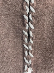 Détail de tissu tricoté marron avec lacets croisés gris et texture pelucheuse