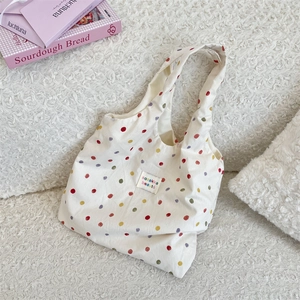 Détail du sac cabas en toile blanche à pois colorés avec étiquette de marque tissée