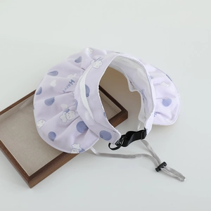 Détail d'une visière enfant violette avec motifs cartoon et jugulaire réglable