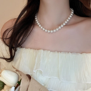 Elegant white pearl necklace worn by a model, showing sophisticated French style texture