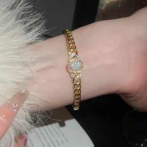 Détail du bracelet gourmette doré avec pièce centrale ovale en zircone étincelante au poignet